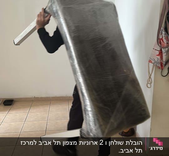 אדם נושא רהיט עטוף בניילון בחדר ריק